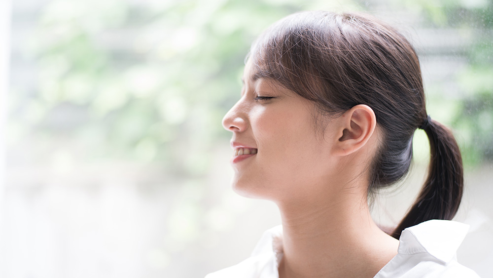 目を閉じてほほ笑む女性
